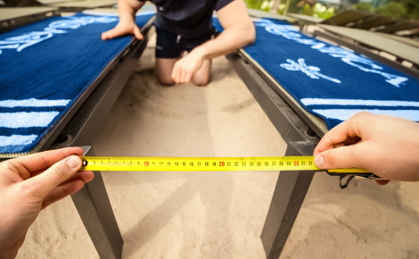 Zwei Mitarbeiter des Europa-Park messen den Abstand zwischen zwei Tischen mit einem gelben Maßband.