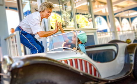 Eine Europa-Park Mitarbeiterin klatscht einen kleinen Jungen ab, der in einem Wagen des Lada Autodrom sitzt.