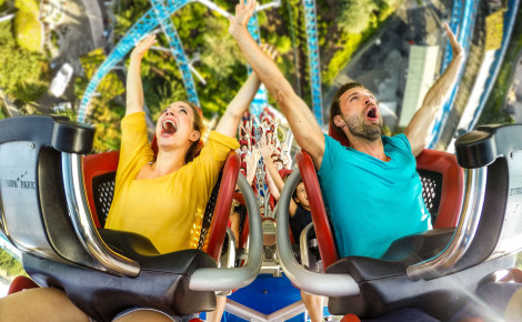 Eine Frau und ein Mann fahren blue fire Megacoaster im Europa-Park. Beide strecken ihre Arme vor Freude nach oben.